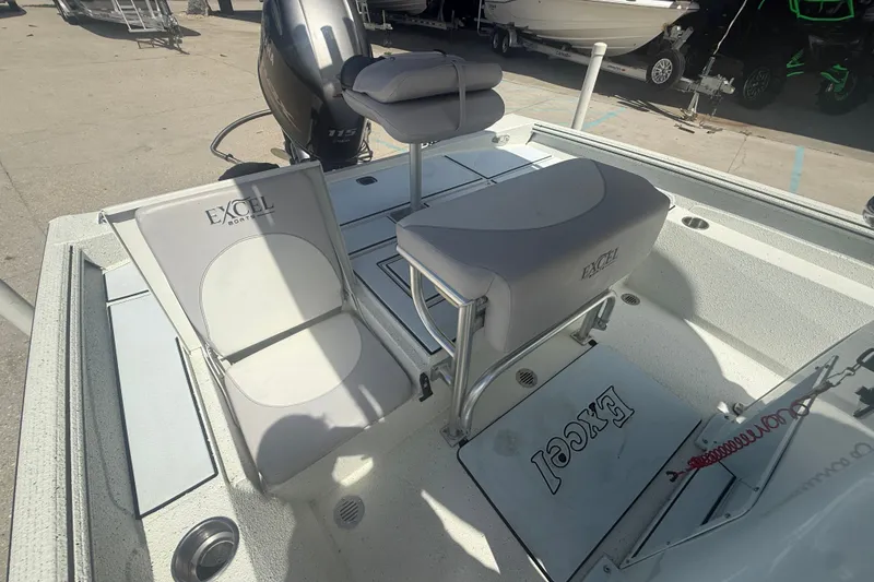 Slide: The Image of 2021 Excel 203 Bay Pro boat interior with seating and motor, parked outdoors. - 11
