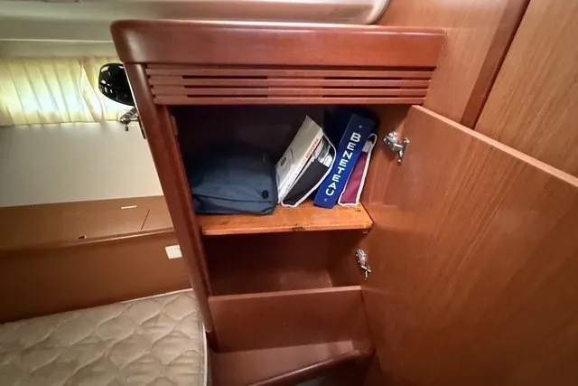Slide: The Image of Wooden cabinet in a 2008 Beneteau Oceanis 46 yacht interior with manuals and storage. - 62