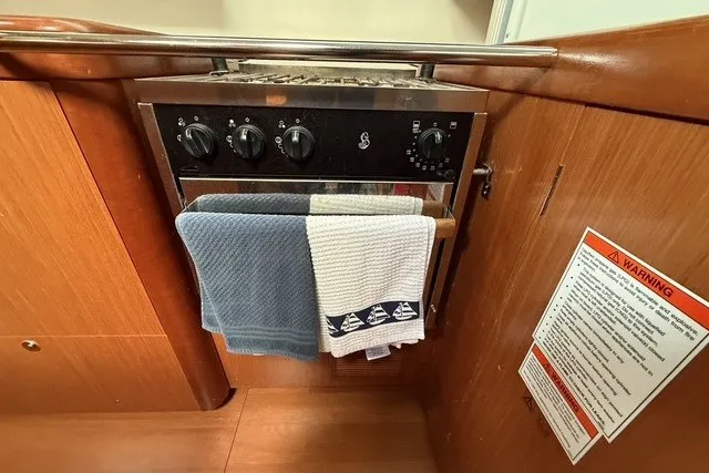 Slide: The Image of Galley oven in 2008 Beneteau Oceanis 46 yacht with towels and safety notice. - 38