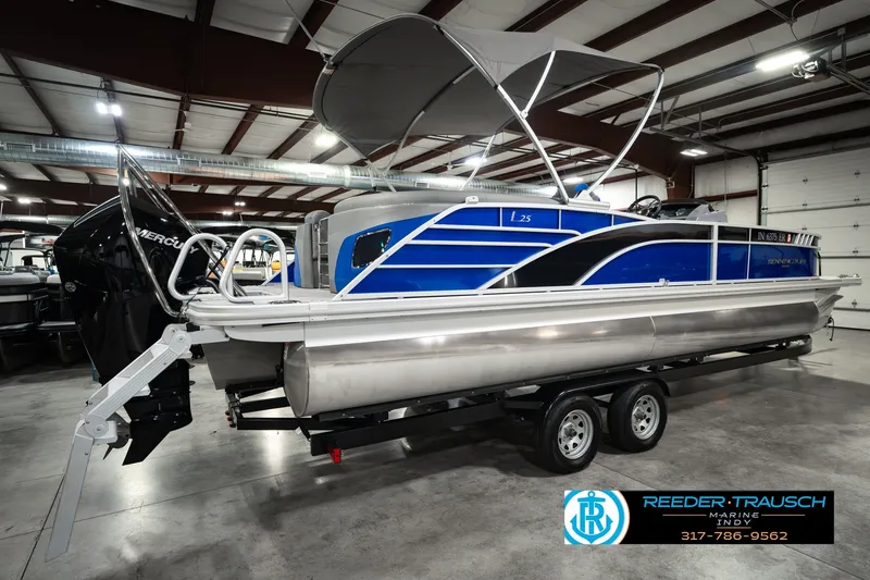Slide: The Image of 2025 Bennington L 25 Quad Bench Bowrider pontoon boat in showroom, blue and silver design. - 8