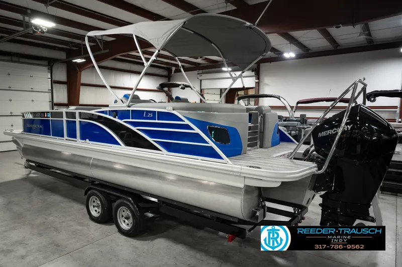 Slide: The Image of 2025 Bennington L 25 Quad Bench Bowrider in showroom, featuring sleek blue design and Mercury engine. - 10