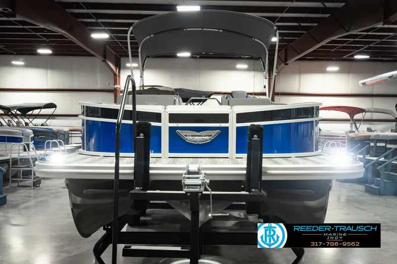 Slide: The Image of 2025 Bennington L 25 Quad Bench Bowrider in showroom, featuring sleek blue design. - 4