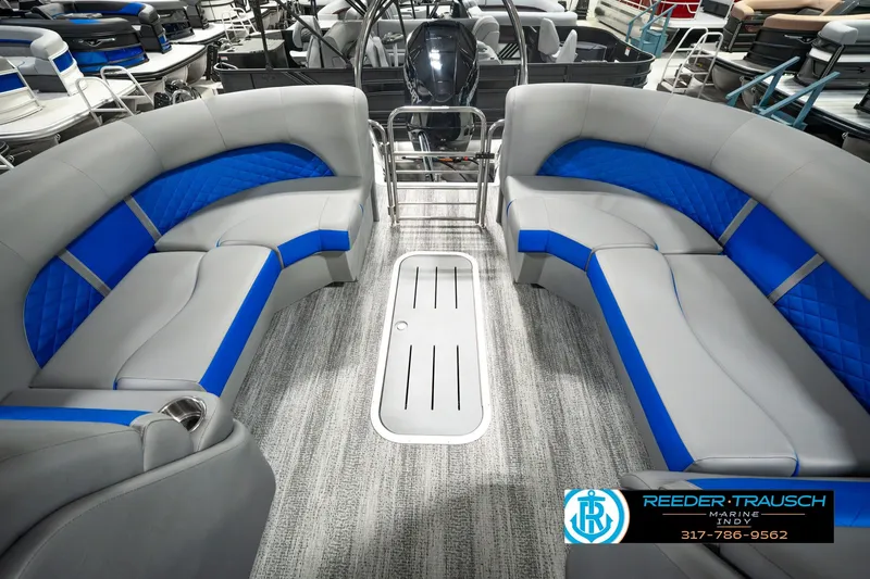 Slide: The Image of 2025 Bennington L 25 Quad Bench Bowrider interior with blue and gray seating, showroom display. - 21