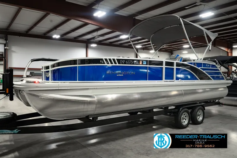 Slide: The Image of 2025 Bennington L 25 Quad Bench Bowrider pontoon boat in showroom on trailer. - 2
