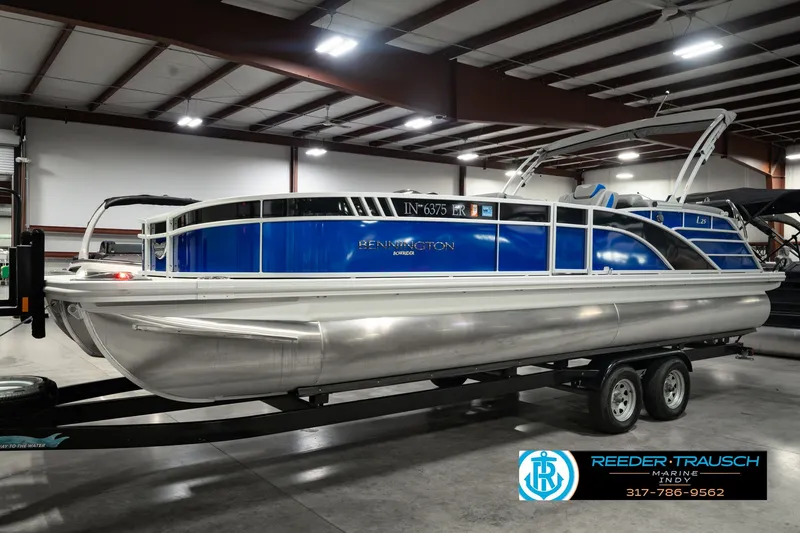 Slide: The Image of 2025 Bennington L 25 Quad Bench Bowrider on trailer in indoor showroom. - 1