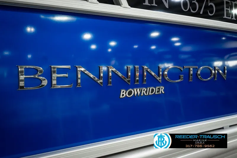 Slide: The Image of 2025 Bennington L 25 Quad Bench Bowrider boat with blue exterior and chrome lettering. - 56