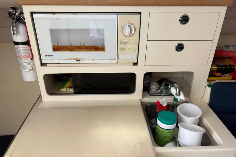 Slide: The Image of Compact kitchen area in a 1998 Albin 28 Tournament Express boat with microwave and sink. - 4