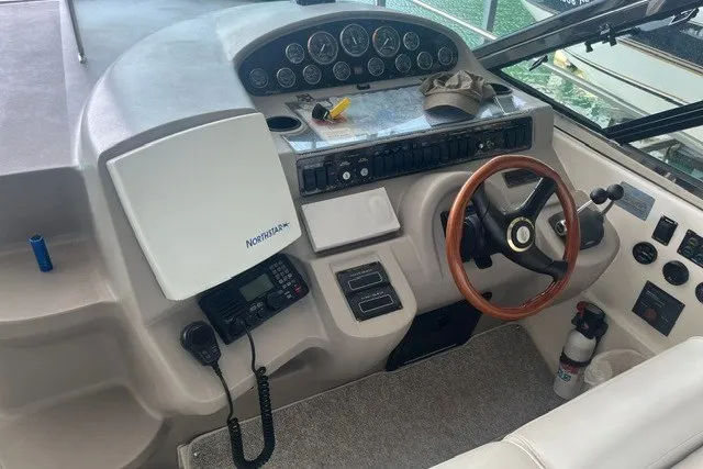 Slide: The Image of 2001 Cruisers Yachts 4270 Express helm with gauges, wooden steering wheel, and navigation equipment. - 13