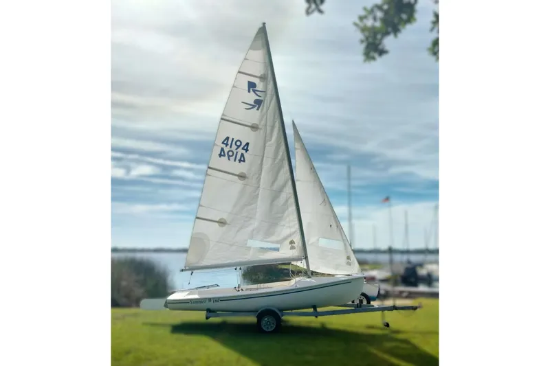 The Image of Sailboat on trailer, Rebel Mark IV 2001, by a lake under a cloudy sky. - 1