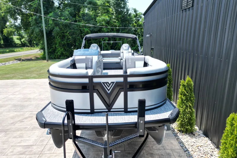 Slide: The Image of 2027 Viaggio Lago X-S 24 pontoon boat on trailer, parked near a metal building. - 17