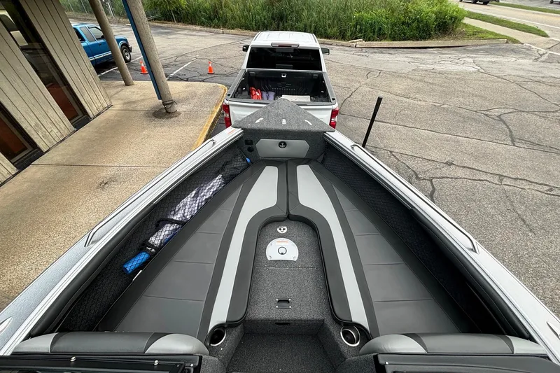 Slide: The Image of 2025 Lund 2275 Baron boat interior with sleek seating and storage, parked near a pickup truck. - 24