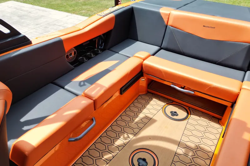 Slide: The Image of 2022 MasterCraft NXT24 boat interior with orange and gray seating, cup holders, and hexagonal flooring. - 8