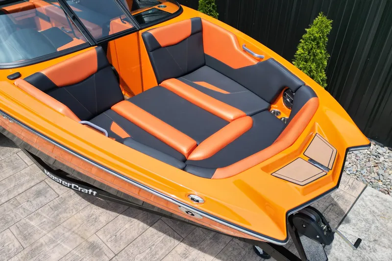 Slide: The Image of 2022 MasterCraft NXT24 boat with vibrant orange and black seating, docked on a wooden platform. - 4