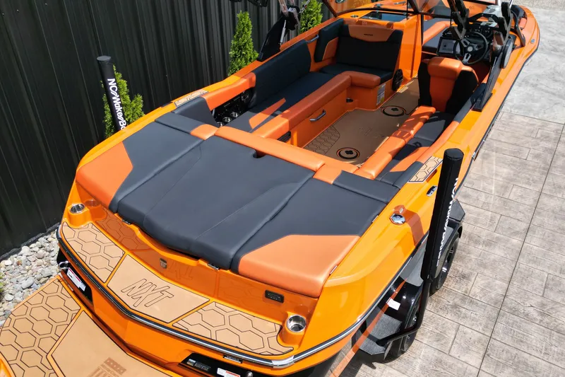 Slide: The Image of 2022 MasterCraft NXT24 boat with orange and black interior, docked on a sunny day. - 6