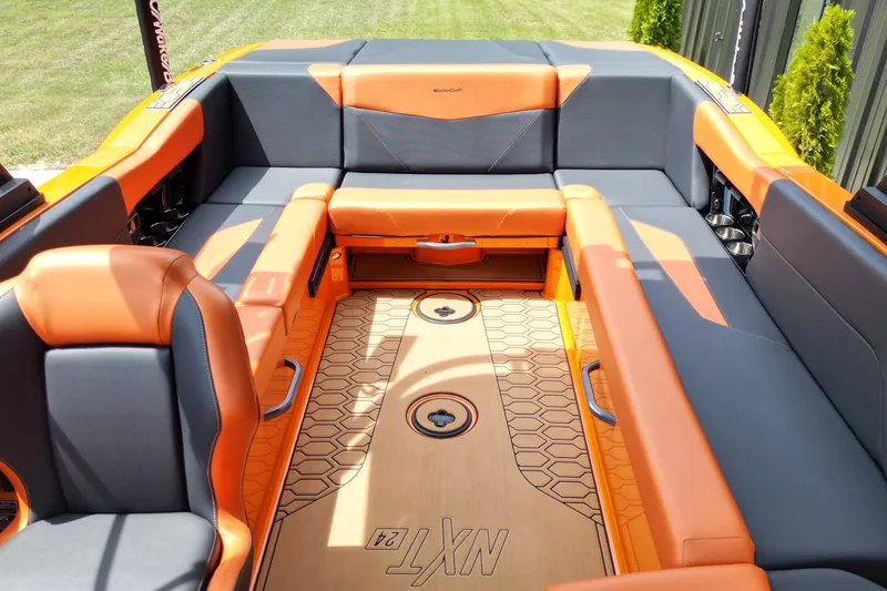 Slide: The Image of 2022 MasterCraft NXT24 boat interior with orange and gray seating, hexagonal floor design. - 15