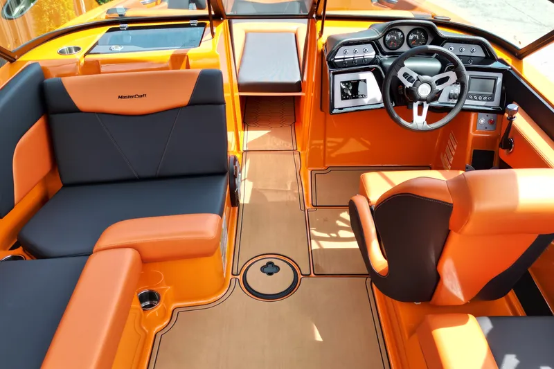 Slide: The Image of 2022 MasterCraft NXT24 boat interior with orange and black seating, modern dashboard, and steering wheel. - 7