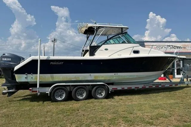 The Image of 2010 Pursuit OS 285 Offshore boat on trailer, parked outdoors under a cloudy sky. - 0