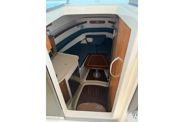 Slide: The Image of 2010 Pursuit OS 285 Offshore cabin interior with seating and wooden table. - 50