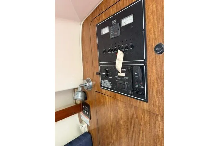 Slide: The Image of Electrical panel inside 2010 Pursuit OS 285 Offshore boat, featuring wood paneling and control switches. - 63