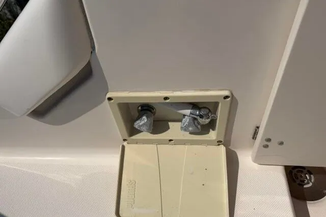 Slide: The Image of 2010 Pursuit OS 285 Offshore boat faucet with open cover, showcasing dual knobs. - 27