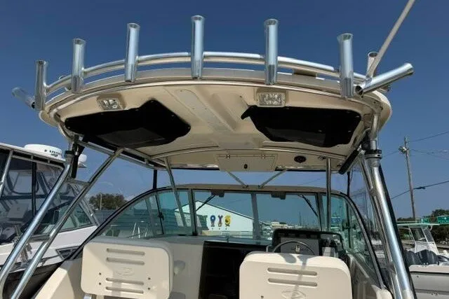 Slide: The Image of 2010 Pursuit OS 285 Offshore boat with rod holders and seating, under clear blue sky. - 32