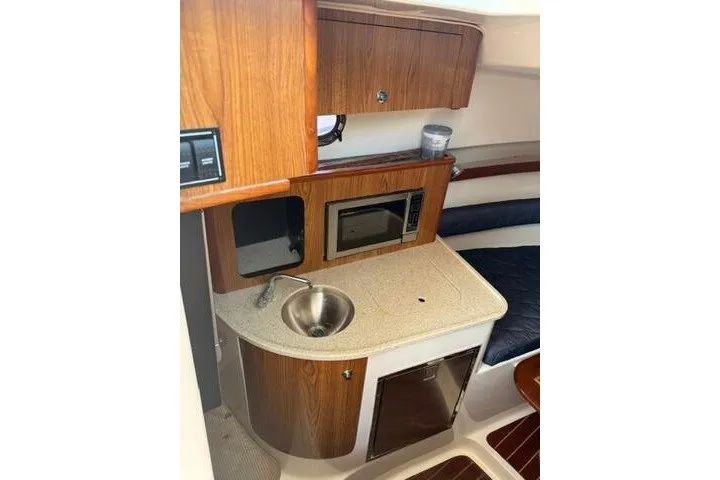Slide: The Image of 2010 Pursuit OS 285 Offshore boat interior with kitchenette, sink, and microwave. - 51