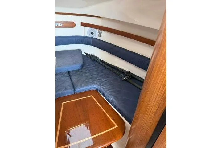 Slide: The Image of 2010 Pursuit OS 285 Offshore cabin interior with blue seating and wooden table. - 61