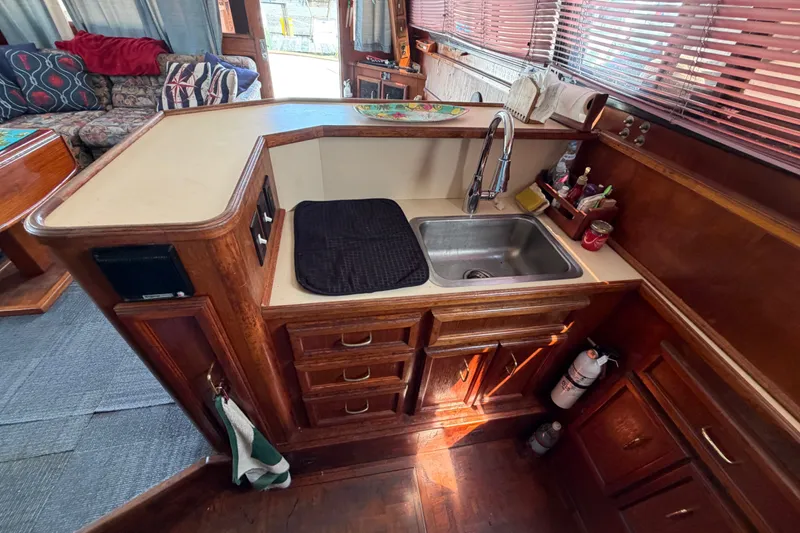 Slide: The Image of Interior of 1989 Egg Harbor 41 Convertible yacht, featuring a compact kitchen with wooden cabinetry. - 17