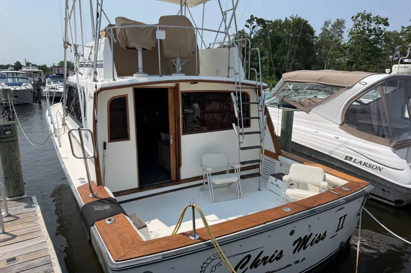 Slide: The Image of 1989 Egg Harbor 41 Convertible yacht docked at marina, featuring spacious deck and ladder. - 6