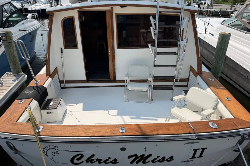 Slide: The Image of 1989 Egg Harbor 41 Convertible boat docked, featuring a spacious deck with chairs and wooden accents. - 7