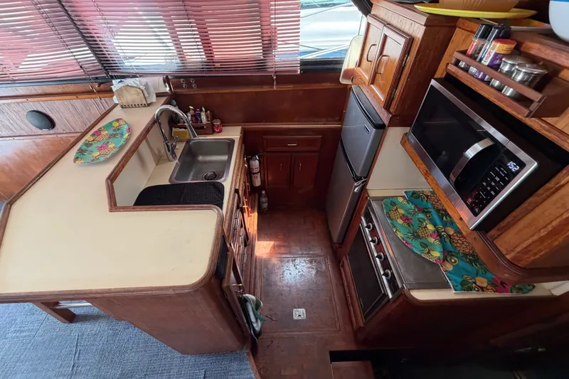 Slide: The Image of 1989 Egg Harbor 41 Convertible yacht kitchen with wooden cabinetry, sink, microwave, and stove. - 16