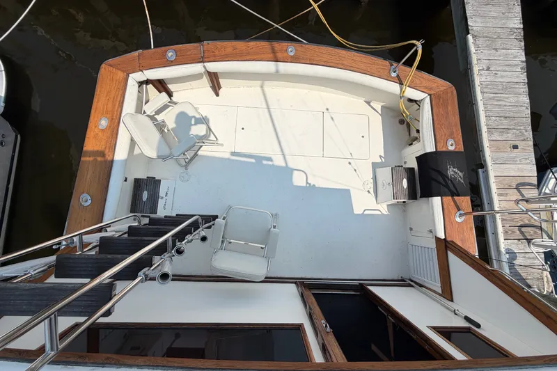 Slide: The Image of 1989 Egg Harbor 41 Convertible boat deck with chairs and wooden trim, docked at marina. - 34