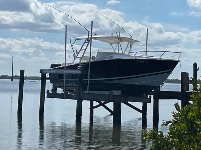 Slide: The Image of 2001 Jupiter 31 Cuddy boat on lift over calm water, under cloudy sky. - 1