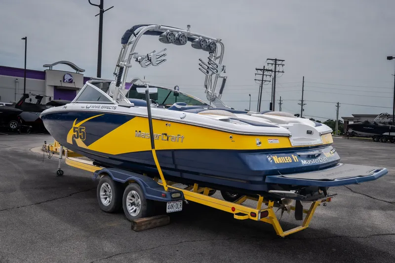 Slide: The Image of 2012 MasterCraft X55 boat in yellow and blue on a trailer in a parking lot. - 9