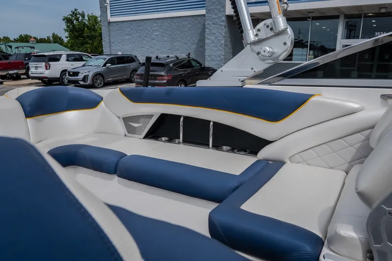 Slide: The Image of 2012 MasterCraft X55 boat interior with blue and white seating, parked near a dealership. - 45