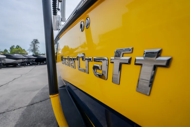 Slide: The Image of Yellow 2012 MasterCraft X55 boat with chrome logo in a marina setting. - 15