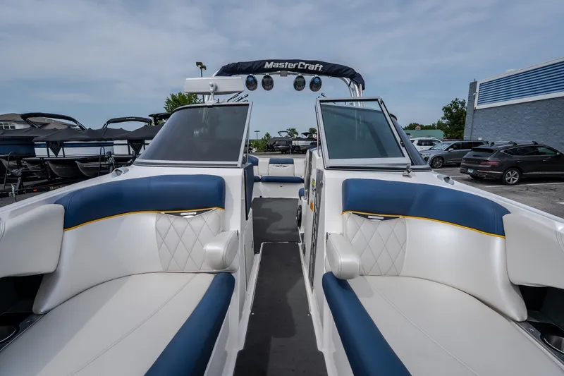Slide: The Image of 2012 MasterCraft X55 boat interior with blue and white seating, docked outdoors. - 35