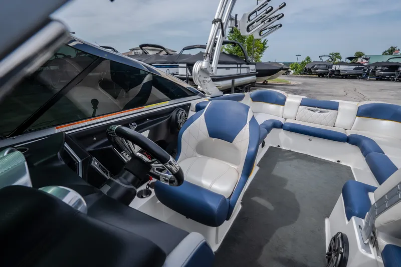 Slide: The Image of 2012 MasterCraft X55 boat interior with blue and white seating, steering wheel, and wakeboard tower. - 37