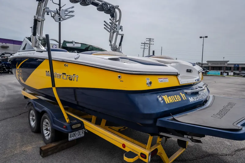 Slide: The Image of 2012 MasterCraft X55 boat in yellow and blue on a trailer, parked outdoors. - 4