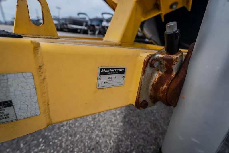 Slide: The Image of Yellow MasterCraft X55 trailer detail with rust, showcasing model and serial number plate. - 13