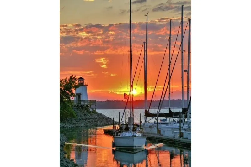 Slide: The Image of Sailboats docked at sunset near a lighthouse, featuring a 1993 Hunter Marine 30. - 4