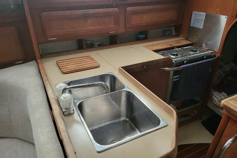 Slide: The Image of 1993 Hunter Marine 30 yacht kitchen with sink, stove, and wooden cabinetry. - 3