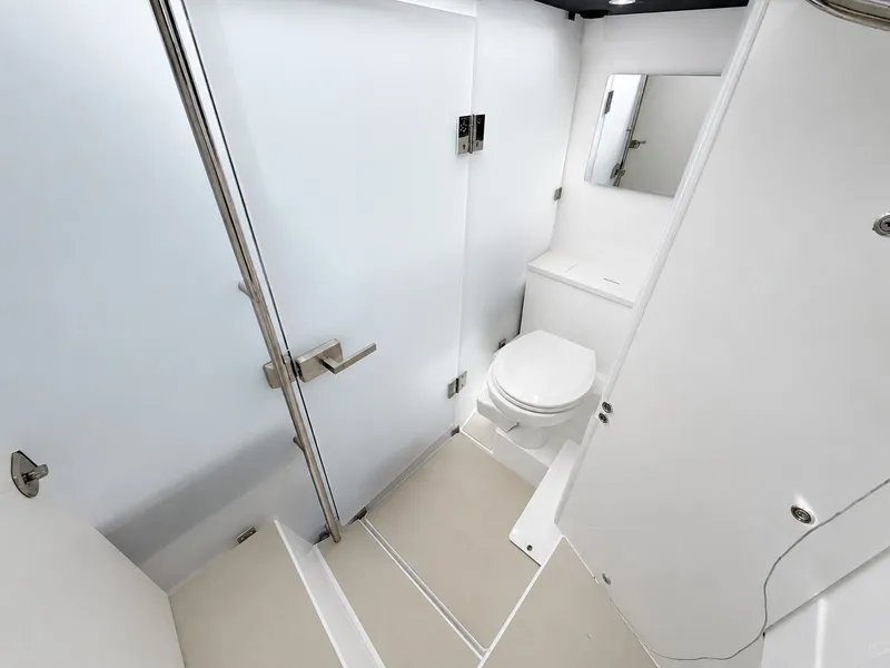 Slide: The Image of The image shows a modern yacht bathroom with a toilet, mirror, and shower. - 32