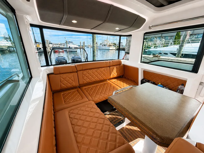 Slide: The Image of Interior of the 2022 Axopar Brabus 37 XC Cross Cabin with brown leather seating and a wooden table. - 24