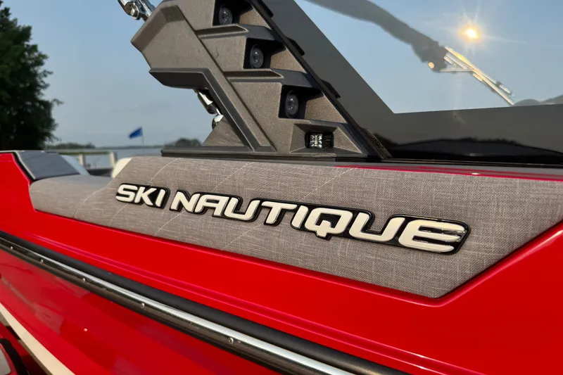 Slide: The Image of 2024 Nautique Ski Nautique boat, red exterior, close-up of logo and windshield. - 9