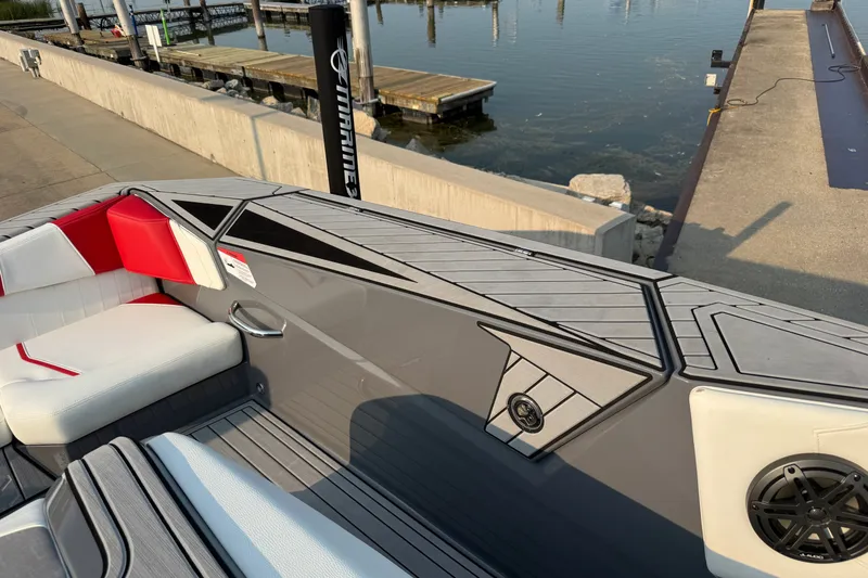 Slide: The Image of 2024 Nautique Ski Nautique boat interior with red and white seating, dockside view. - 8