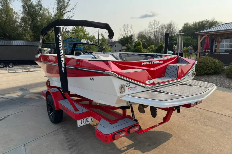 Slide: The Image of 2024 Nautique Ski Nautique boat in red and white on a trailer, parked outdoors. - 5