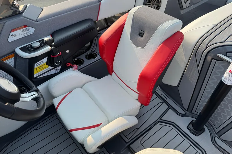 Slide: The Image of 2024 Nautique Ski Nautique interior with red and white seating, modern controls, and cup holders. - 32