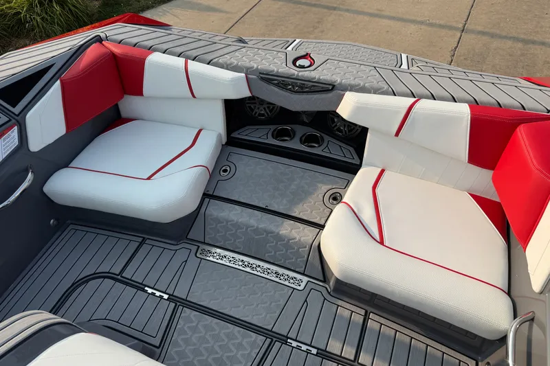Slide: The Image of 2024 Nautique Ski Nautique interior with red and white seating, gray flooring, and cup holders. - 14