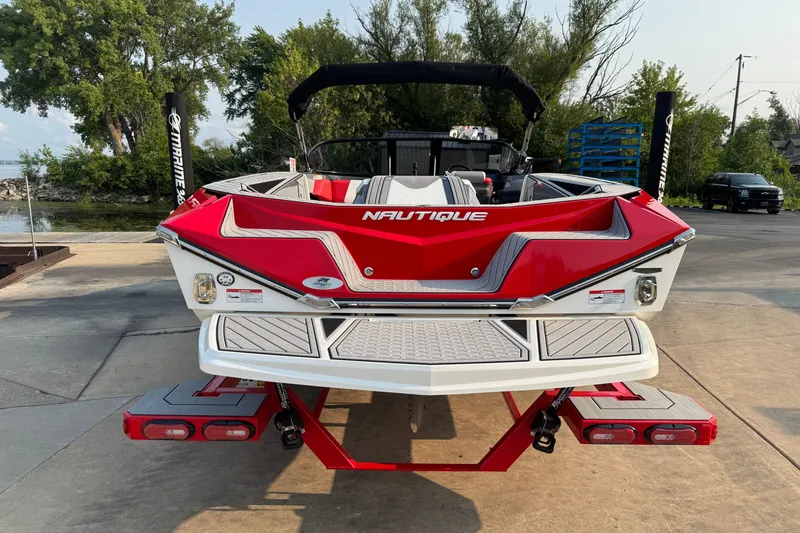 Slide: The Image of 2024 Nautique Ski Nautique boat, red and white, parked near a lake. - 6